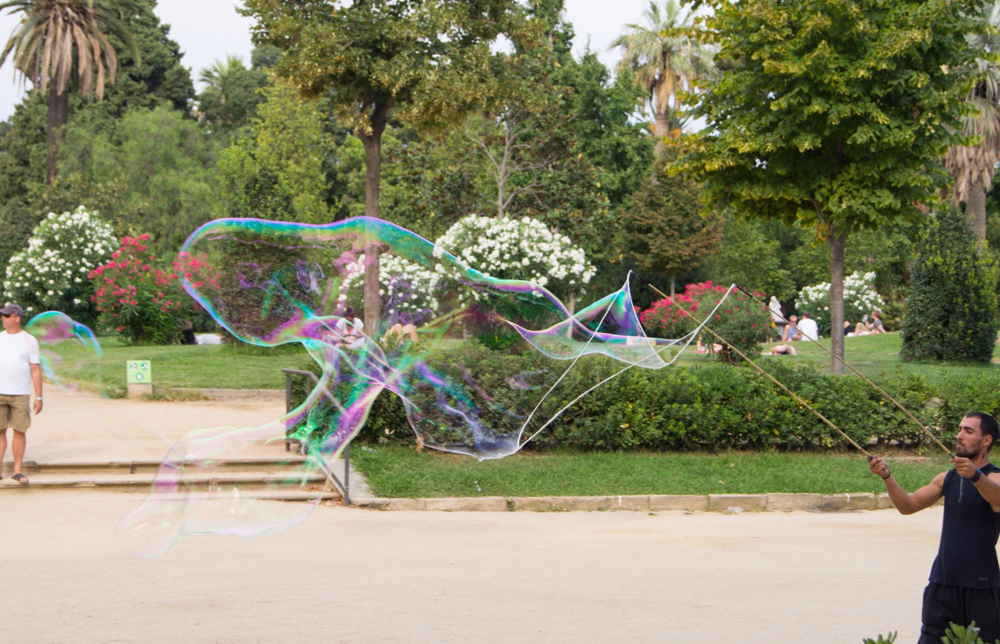 Street performer blows a huge bubble in Parc de la Ciutadella, Barcelona