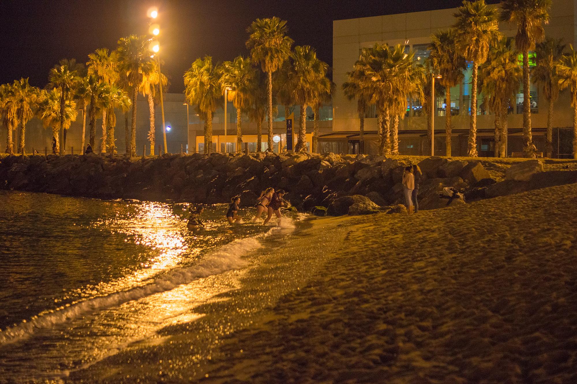 Group of females runs out of water after a night swim on the beach of Sant Sebastia in Barcelona in February