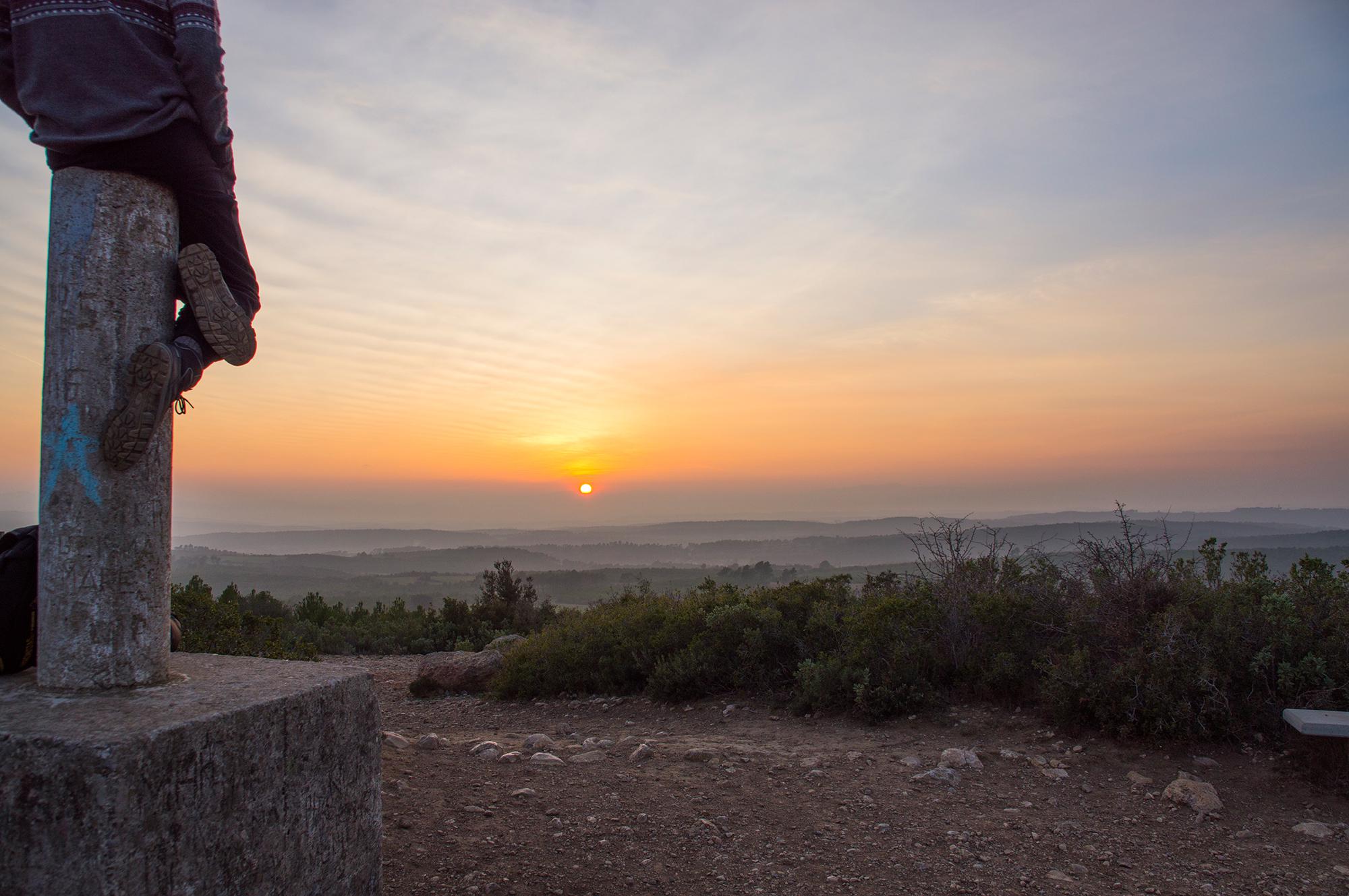 Young man admires the sunset over the hills near the village of Garrigolies in the province of Girona in Catalonia